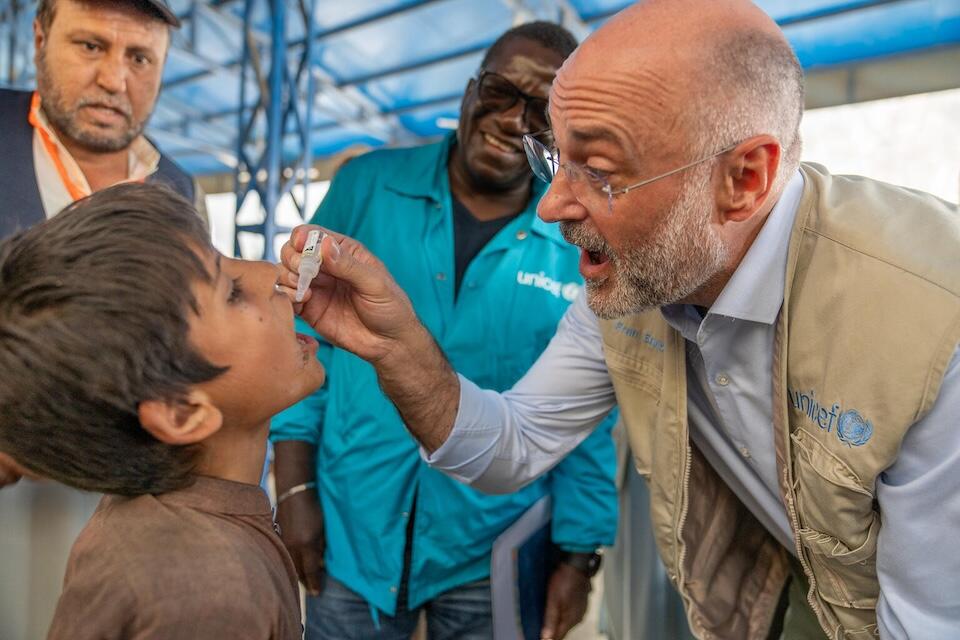 On Nov. 7, 2023, UNICEF Representative in Afghanistan Fran Equiza gives a polio vaccine to a young boy, who has just returned to Afghanistan from Pakistan with his family.
